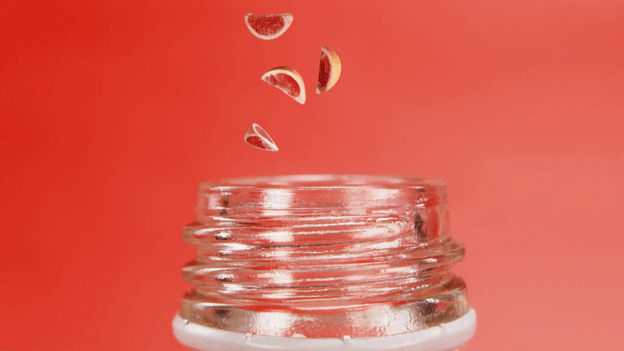 Fruit falling into a glass bottle against red, from the GuS shoot