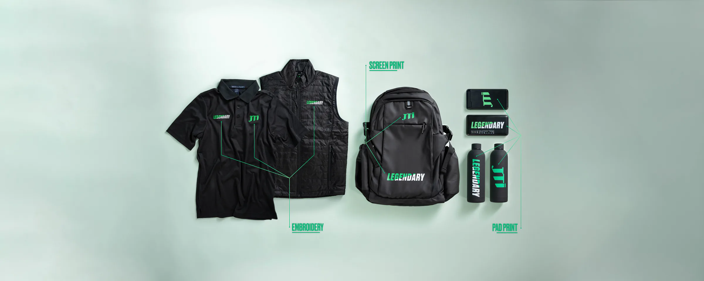 The JTI Legendary kit laid out: an embroidered polo and vest, a screen-printed backpack, pad-printed power banks and bottles