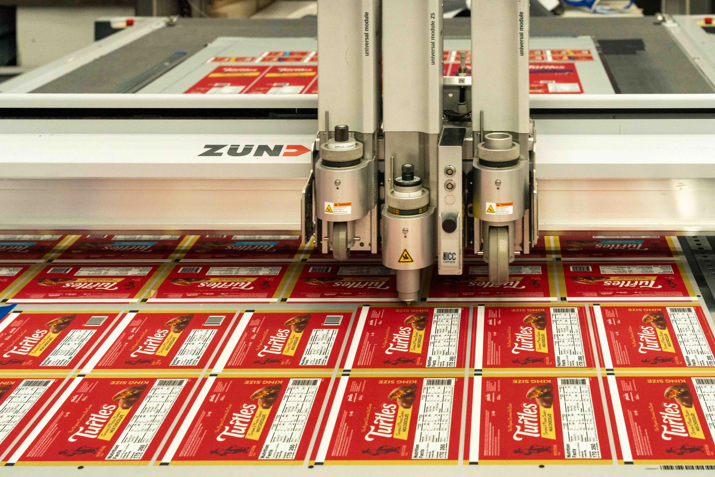 The Zünd cutter working through a sheet of Turtles boxes