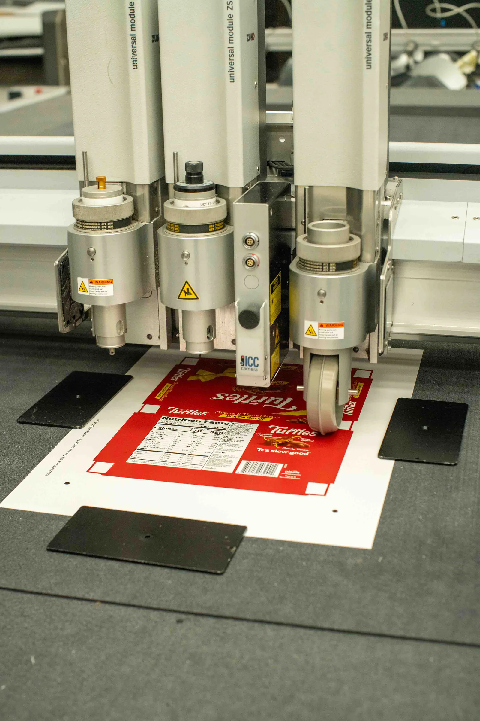 The Zünd cutter’s heads over a printed sheet of Turtles boxes